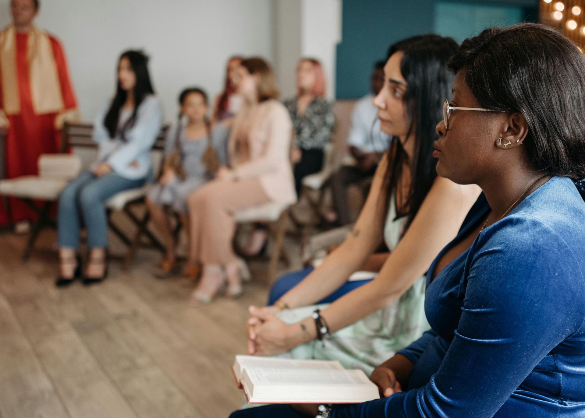 A diverse group of people in a church setting, engaged in prayer and reflection, holding a holy book.